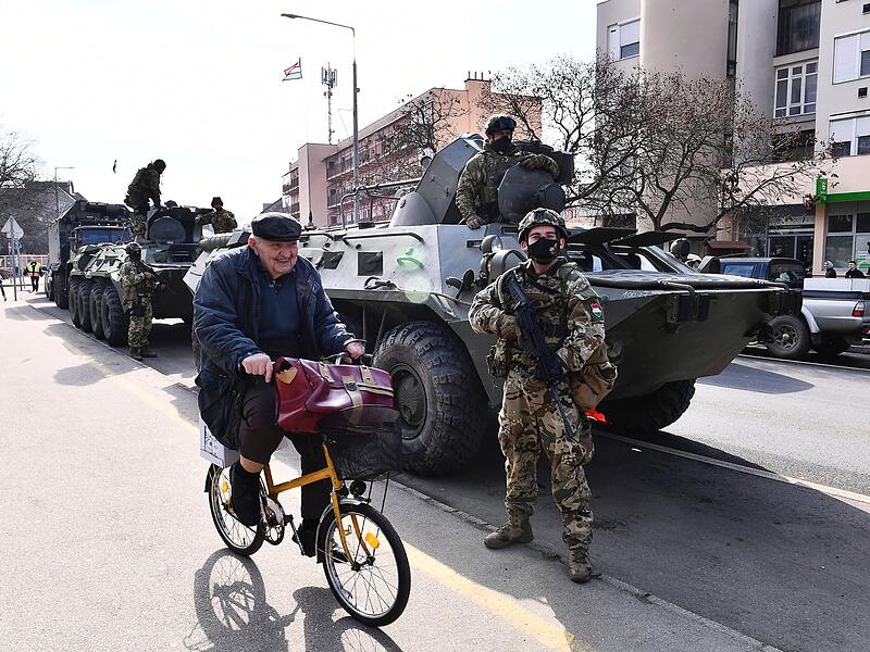 Ein Radfahrer fährt an einer Kolonne gepanzerter Fahrzeuge der ungarischen Armee in der Stadt Vasarosnameny vorbei. Ungarn hat seine Streitkräfte in die östlichen Gebiete nahe der ukrainischen Grenze verlegt, um bei den Vorbereitungen auf die Ankunft von Flüchtlingen zu helfen.