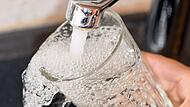 Eine Frau füllt ein Glas mit Trinkwasser aus dem Hahn