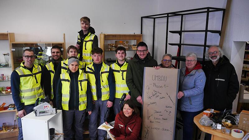Dominik Schneider und Maximilian Schuhmann möbeln mit ihren Azubis den Weltladen auf. Daneben (von links) Bürgermeister Jan Marberg, Vereinsmitglied Brigitte Conzelmann, Stadträtin Monika Wiesner und Vorsitzender Dirk Hönerlage, vorne unten Weltla...