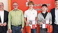 Vorstandsvorsitzender Stephan Kirchner (links) und Wertpapierbeauftragter David Förtsch (rechts) gratulieren Samuel Ziegelhöfer und Leon Motschenbacher vom Siegerteam „Gejagt vom Finanzamt“ vom Clavius-Gymnasium, zusammen mit ihrem Lehrer Jürgen S...