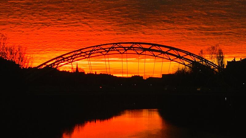 Die Luitpoldbrücke in Bamberg im roten Licht: Saharastaub führt oft zu farbenprächtigen Sonnenaufgängen.
