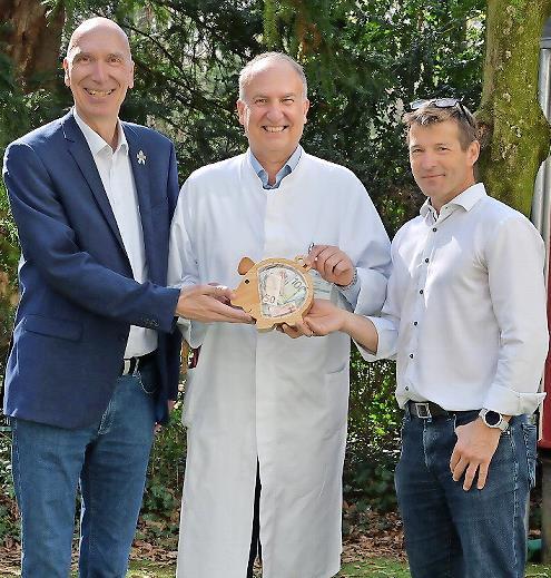 Holger Schmidt (l.) und Steffen Polster (r., beide Siemens Healthineers) &uuml;berreichten Prof. Dr. Joachim W&ouml;lfle das randvolle &bdquo;Spendenschweinchen&ldquo;.