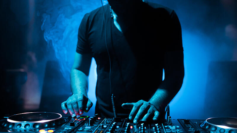 DJ mixing tracks on a mixer in a nightclub