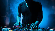 DJ mixing tracks on a mixer in a nightclub