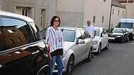 Die Initiatoren des Bürgerantrages Elisabeth Ollmann und Bernhard Fischer vor den parkenden Autos.