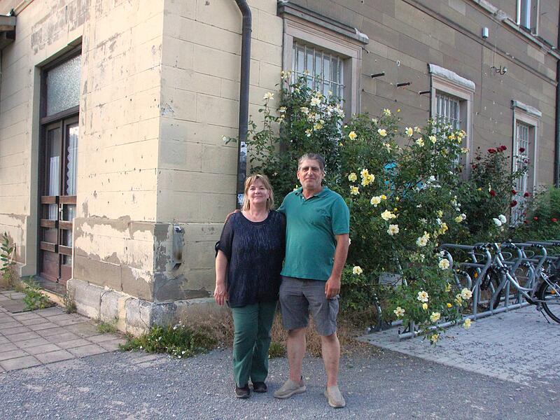 Susanne Hanshans und Cem Erkul stehen vor dem Bahnhof M&uuml;nnerstadt. Der Raum hinter ihnen soll der Gastraum f&uuml;r Hanshans' neue Gastronomie werden.