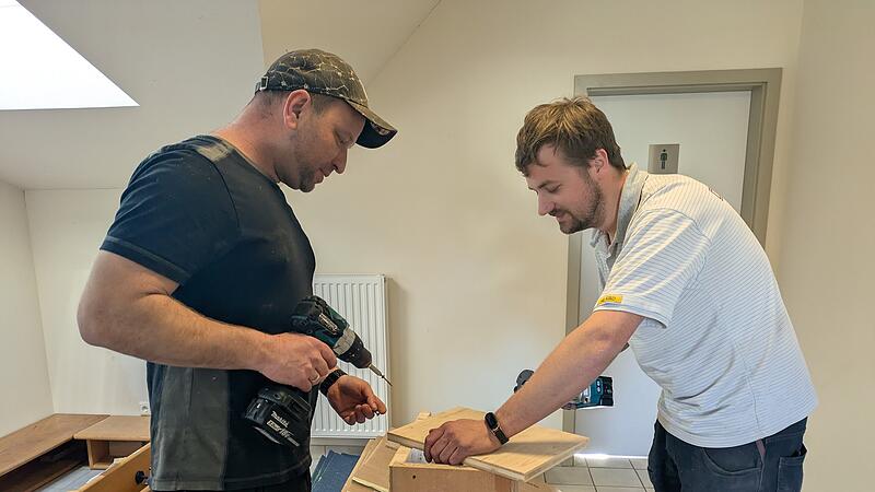 Zwei Papas basteln die Garderobe zurecht.