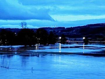 In den &uuml;berfluteten Wiesen im Saaletal spiegeln sich die Lichter der Stra&szlig;enbeleuchtung. Auch die Hammelburger Stadtpfarrkirche und das Rote Schloss leuchten &bdquo;strahlend sch&ouml;n&ldquo;.