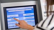 Frau hebt Geld an einem Automaten ab