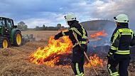 Ein Landwirt und zwei Feuerwehrkr&auml;fte versuchen,  einen Feldbrand bei Lautertal zu kontrollieren.