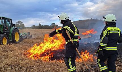 Ein Landwirt und zwei Feuerwehrkr&auml;fte versuchen,  einen Feldbrand bei Lautertal zu kontrollieren.