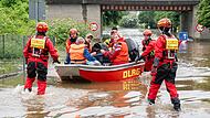 Die Helfer evakuieren mit Booten Menschen, die von den Wassermassen in ihren Häusern eingeschlossen sind.