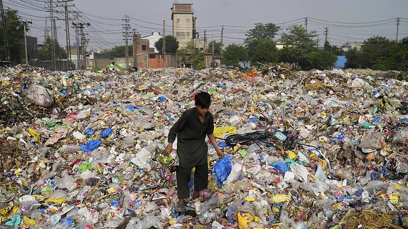 Ein Mann sammelt in Pakistan wiederverwertbares Plastik auf einer Mülldeponie.