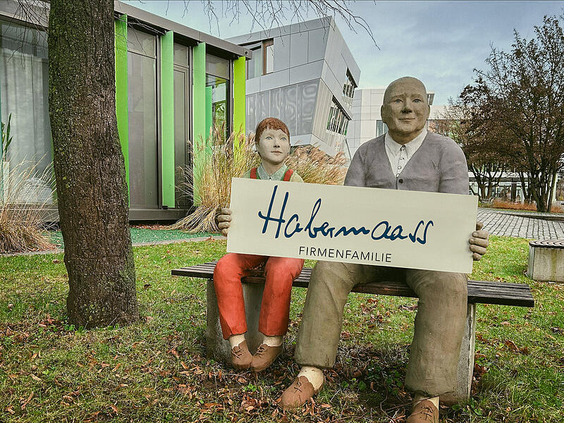 Der Name &bdquo;Haba-Familygroup&ldquo; ist Geschichte. Der Spielwarenhersteller und Kita-Komplettausstatter firmiert jetzt als &bdquo;Habermaass Firmenfamilie&ldquo;. Auf unserer Fotomontage haben die beiden Figuren vor dem Firmensitz in Bad Rodach den neuen Namen bereits in der Hand.