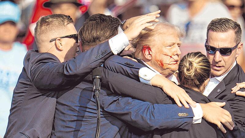 Der republikanische Pr&auml;sidentschaftsbewerber und fr&uuml;here US-Pr&auml;sident Donald Trump wird von Secret-Service-Agenten umringt, als ihm bei einer Wahlkampfveranstaltung von der B&uuml;hne geholfen wird. Trump wurde w&auml;hrend des Wahlkampfes attackiert.