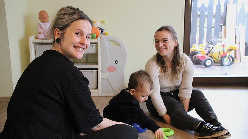 Zwei Frauen sitzen mit einem Kind auf dem Boden.
