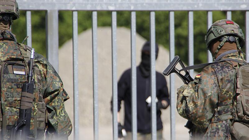 Die Zivilisten vor dem Tor werfen Steine und St&ouml;cke auf die Kameraden der Bundeswehr.