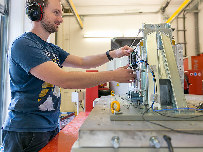 EMCC Dr. RašekForchheim & Fränkische Schweiz Es kommen nicht nur Großgeräte auf den elektromagnetischen Prüfstand: Hier bereitet ein Mitarbeiter einen Prüfling gerade für eine Vibrationsprüfung vor.