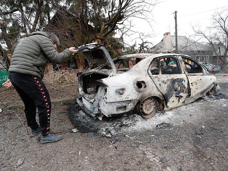 Ein Mann kontrolliert am 28.02. ein verbranntes Auto in dem von Separatisten besetzen Gebiet in der Ostukraine.