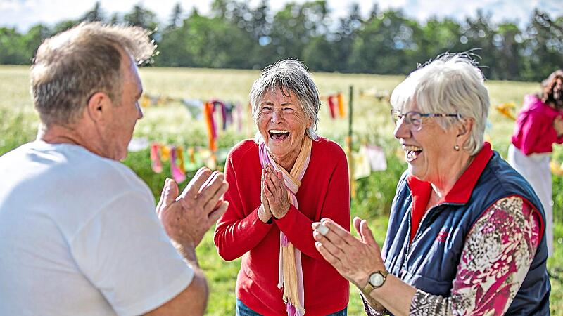 Renate F&ouml;rster steht zwischen den Teilnehmern und lacht herzlich. Ihr angeleitetes Lachen steckt viele in der Gruppe an. Ren&eacute; Ruprecht