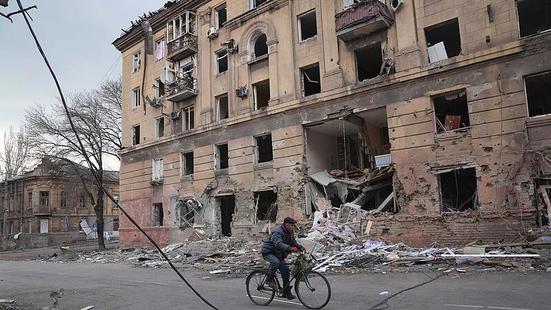 Ein Mann f&auml;hrt mit dem Fahrrad an einem Wohnhaus in Mariupol vorbei. Der Krieg in der Ukraine wird immer brutaler.