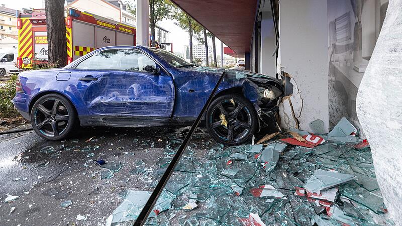 Frau f&auml;hrt mit Auto in M&ouml;belhaus-Schaufenster