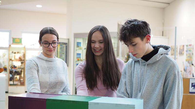 Flavie (von links), Lisa und Viktor probieren gemeinsam die Tastkästen im Coburger Naturkundemuseum aus.