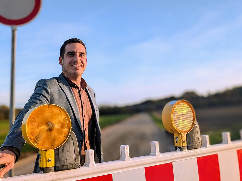 Maximilian Neeb, Bürgermeister der Stadt Seßlach steht vor einem Bauzaun. Maximilian Neeb, Bürgermeister der Stadt Seßlach steht vor einem Bauzaun.