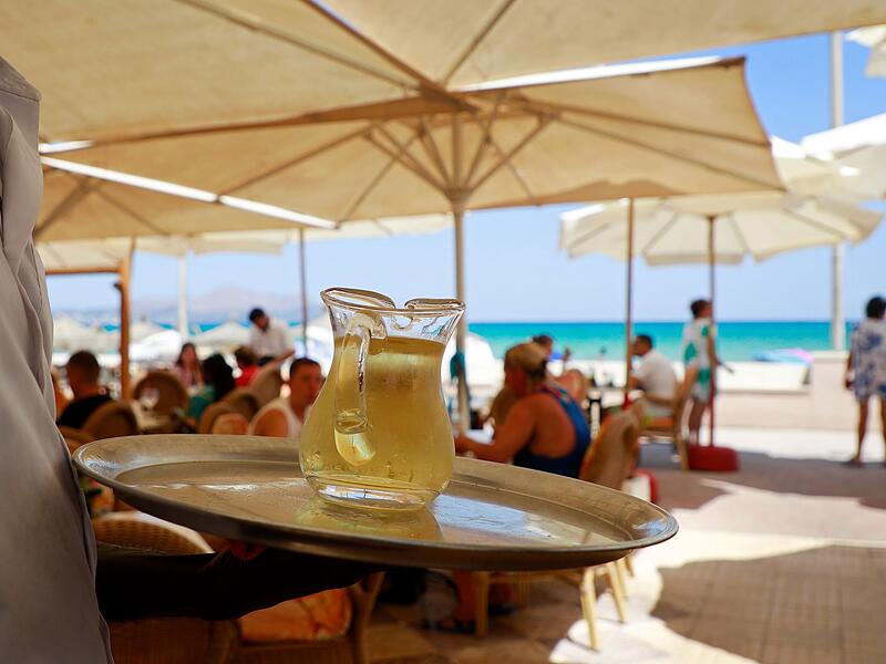Ein Kellner serviert an einem mallorquinischen Strand einen Wein