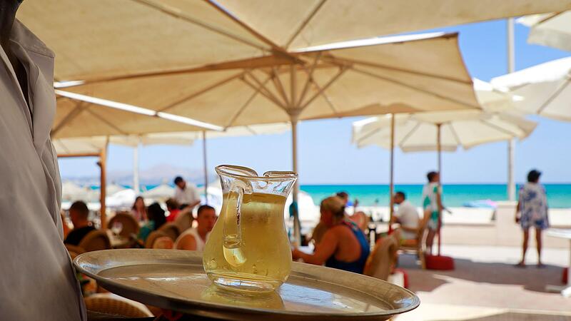 Ein Kellner serviert an einem mallorquinischen Strand einen Wein