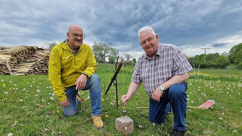 Das Werkzeug der Feldgeschworenen: Walter Muth (links) und Siegfried Schaub demonstrieren das Setzger&auml;t mit Senklot an einem Grenzstein.