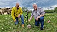 Das Werkzeug der Feldgeschworenen: Walter Muth (links) und Siegfried Schaub demonstrieren das Setzger&auml;t mit Senklot an einem Grenzstein.