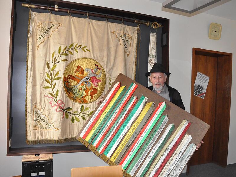 Alois Tremer mit der Fahne des katholischen Burschenvereins Sulzthal in der von ihm gefertigten Vitrine aus dunkler Mooreiche.