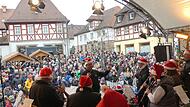 Die Zuschauer auf dem Marktplatz lauschen den ehemaligen Mitgliedern der Stadtjugendkapelle.