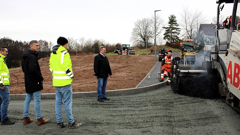 Die Asphaltiermaschine der Firma Strabag arbeitete sich St&uuml;ck f&uuml;r St&uuml;ck im Neubaugebiet Katschenreuth voran, um oberirdisch die notwendige Infrastruktur mit Stra&szlig;en und Gehwegen zu schaffen. Die Stadt Kulmbach hat f&uuml;r die Erschlie&szlig;ung der Baupl&auml;tze in attraktiver Lage mehr als zwei Millionen Euro in die Hand genommen. Oberb&uuml;rgermeister Ingo Lehmann (Vierter von links) &uuml;berzeugte sich zusammen mit Tiefbauchef Frank Wiesel (Zweiter von links) und dem st&auml;dtischen Mitarbeiter Manuel M&uuml;ller (links) pers&ouml;nlich von den abschlie&szlig;enden Asphaltierungsarbeiten in Katschenreuth.