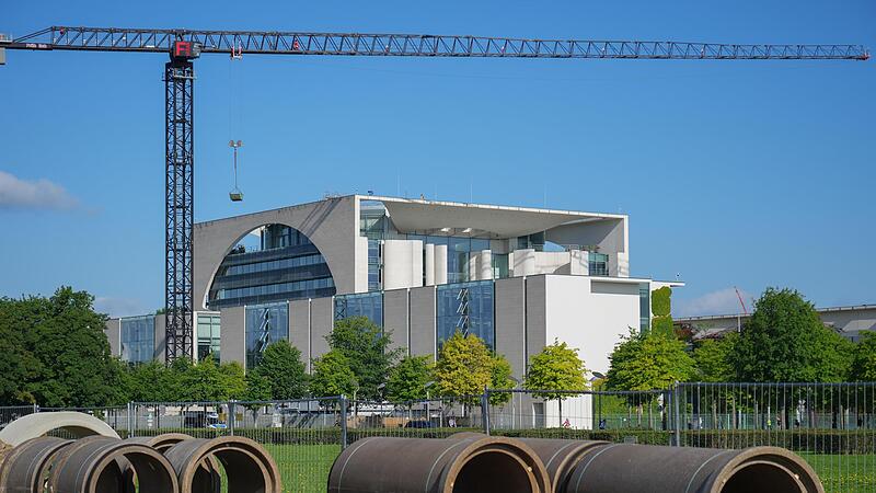 Baumaterial liegt auf der Wiese vor dem Reichstag vor der Kulisse des Kanzleramtes.