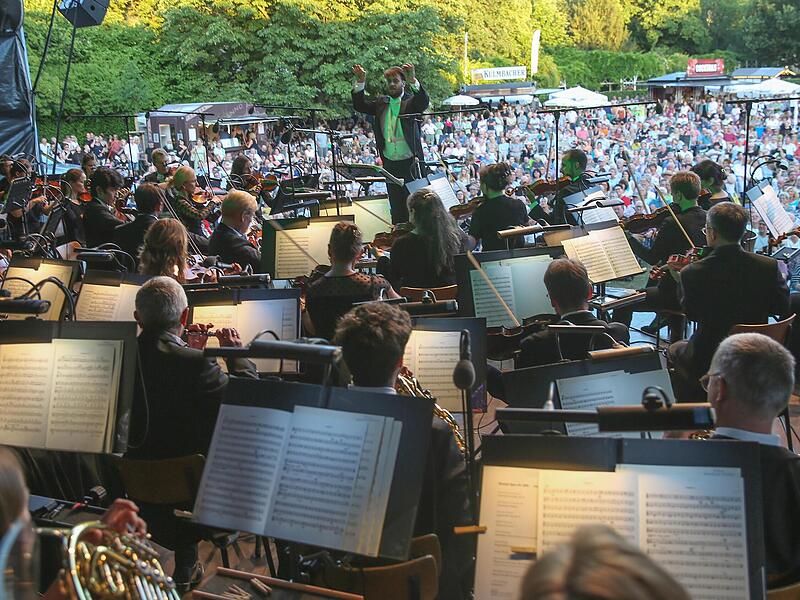 Blick von der B&uuml;hne Richtung Rosengarten: Daniel Carter dirigiert das Philharmonische Orchester beim Klassik-Open-Air im Coburger Rosengarten.