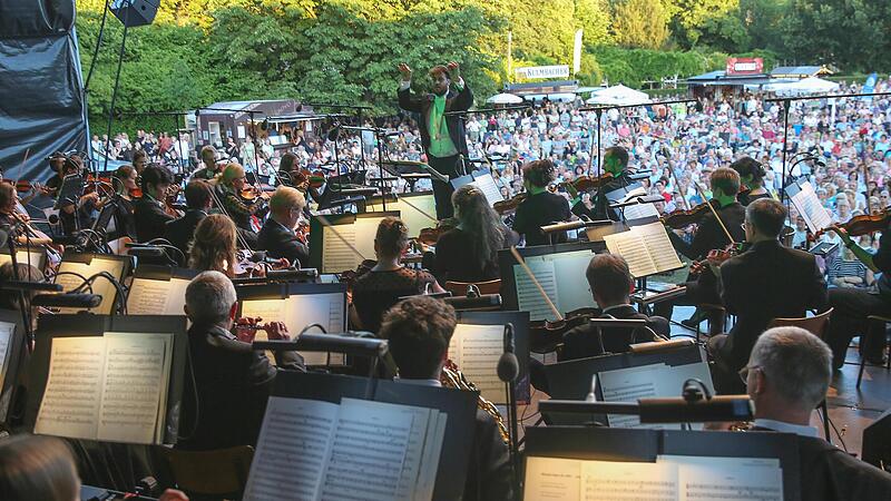 Blick von der B&uuml;hne Richtung Rosengarten: Daniel Carter dirigiert das Philharmonische Orchester beim Klassik-Open-Air im Coburger Rosengarten.