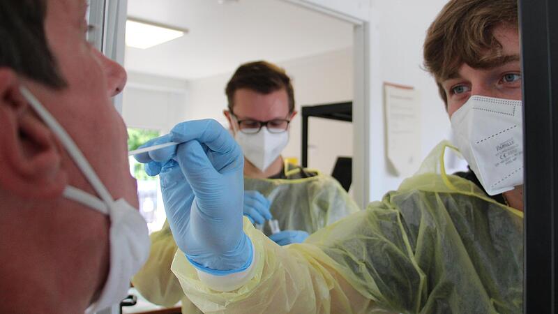 Die ASB-Mitarbeiter Tim Speelmann (rechts) und Lukas Kern nehmen Proben für PCR-Tests im offiziellen Testzentrum am  Großparkplatz in Erlangen. Aber wie lange es das noch geben wird, ist unklar.