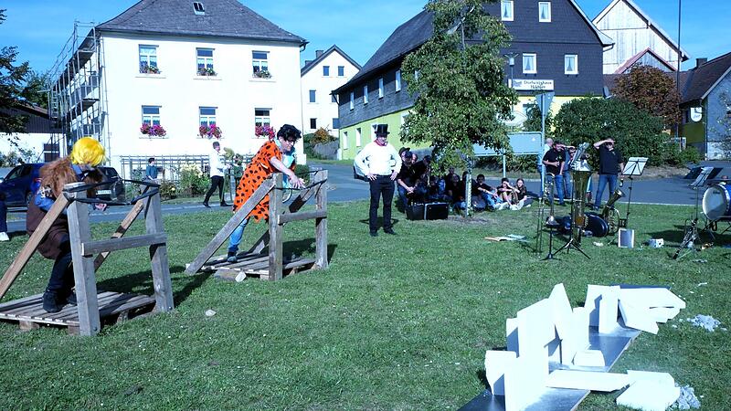 Mit dem Katapult muss eine Mauer eingerissen werden. Links Barney Geröllheimer alias Andreas Roderer, rechts Fred Feuerstein alias Bürgermeister Jens Korn.