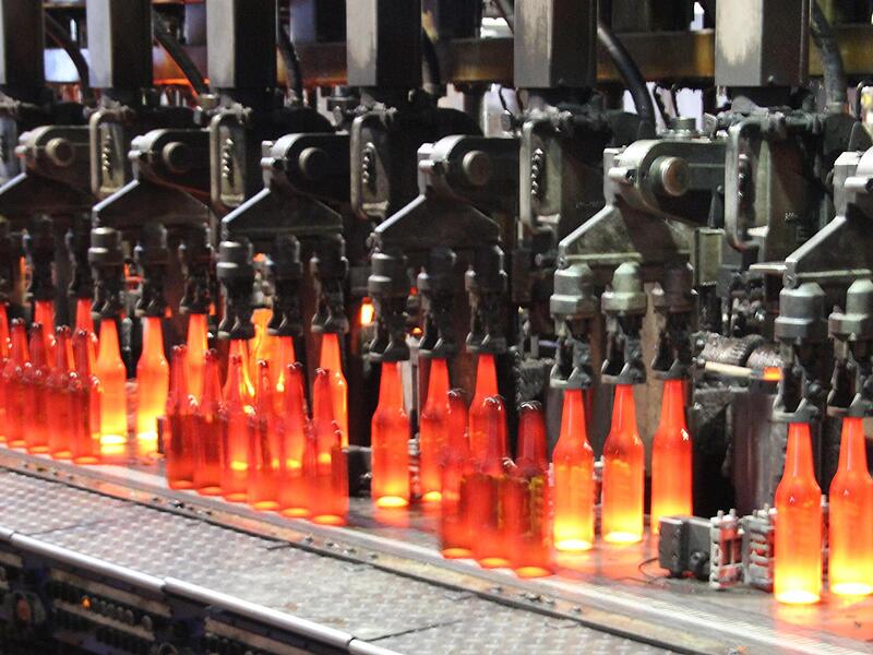 Wie ein präzises Uhrwerk – die Glasautomaten formen aus Glastropfen Flasche um Flasche. Nun geht die Reise weiter Richtung Kühlbahn.