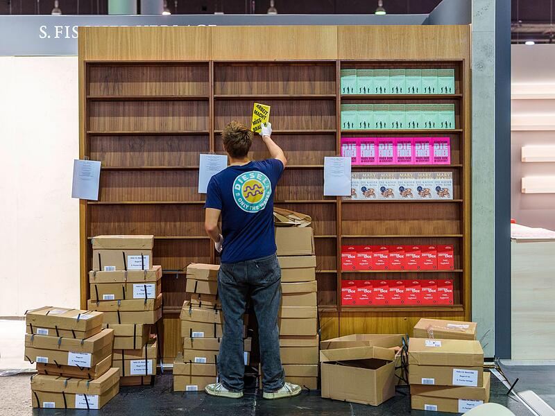 Ein junger Mann r&auml;umt B&uuml;cher in ein Regal ein