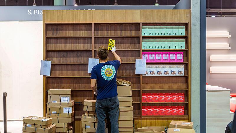 Ein junger Mann räumt Bücher in ein Regal ein Ein junger Mann räumt Bücher in ein Regal ein
