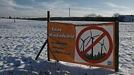 Die Gegner eines Windparks im Ro&szlig;bacher Forst machen erneut mobil, hier mit einem Aufsteller am Ortsrand von Ro&szlig;bach, im Hintergrund das mutma&szlig;lich betroffene riesige Waldst&uuml;ck.