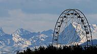 Riesenrad vor schneebedeckten Bergen