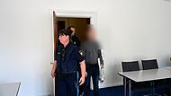 Der Angeklagte wird von zwei Polizeibeamten in den Gerichtssaal gebracht.