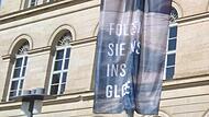 Freundliche Aufforderung: „Folgen Sie uns ins Globe“ heißt es auf dieser Fahne vor dem Landestheater. Das betagte Haus am Schlossplatz wird in wenigen Tagen unweigerlich geschlossen – Beginn der Generalsanierung: völlig offen.