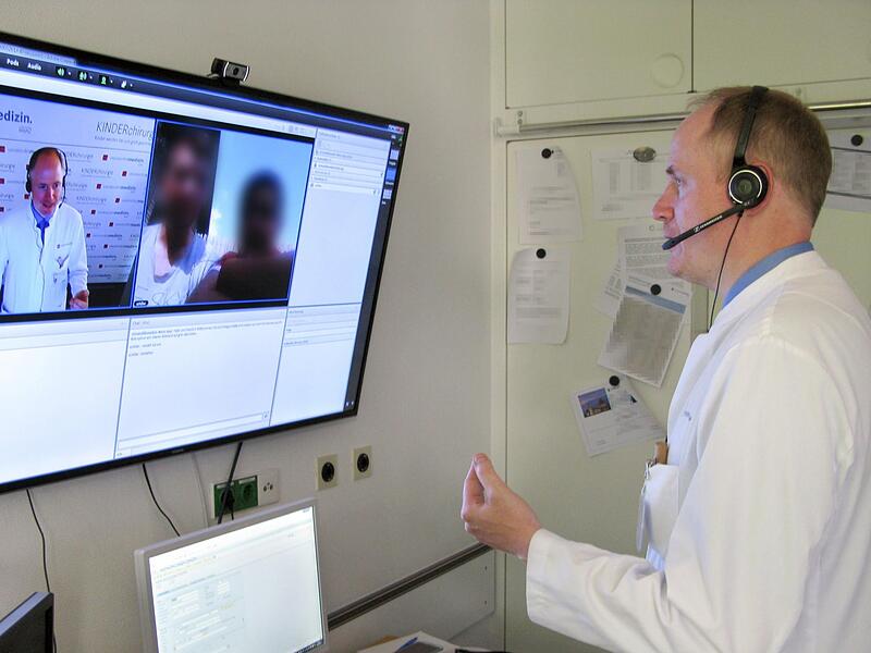 In einem Videoanruf bespricht  ein  Arzt mit seinen Patienten die Behandlung.