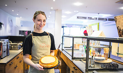 Café Yu No Mitarbeiterin Solène Perron präsentiert einen der glutenfreien Kuchen, die im Café Yu No im Ertl-Zentrum in Hallstadt angeboten werden.