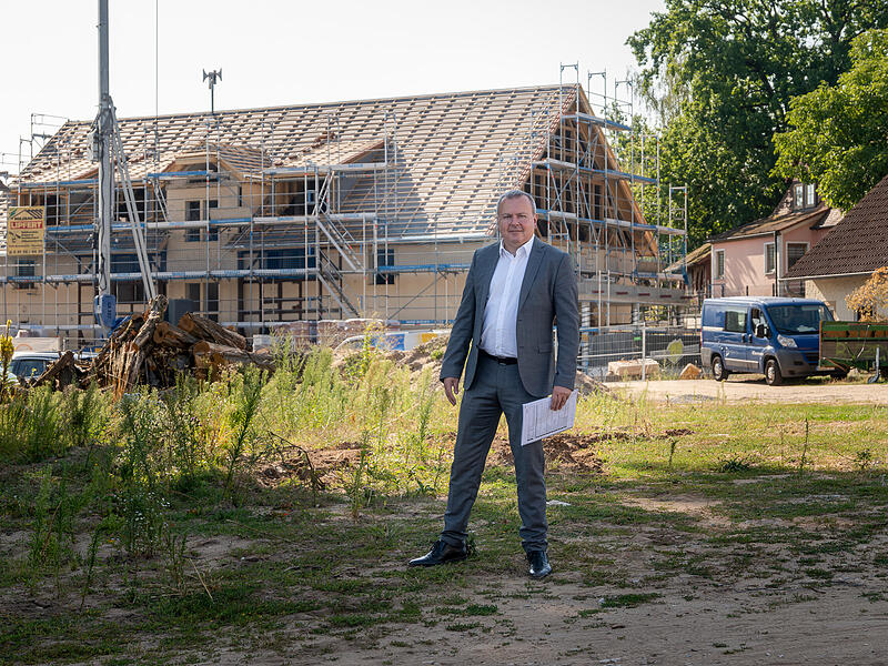 B&uuml;rgermeister Peter Lepper steht auf dem Gel&auml;nde, auf dem das neue Rathausquartier  von Effeltrich entstehen soll. Hinter ihm wird das Rathaus derzeit umfassend saniert.